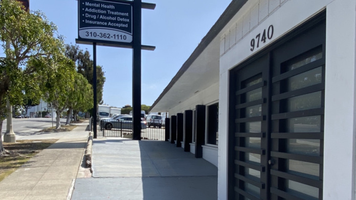 Exterior facade with Forward Recovery pole sign, service information, and black entrance doors with concrete walkway
