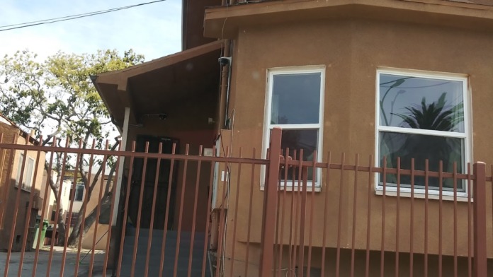Exterior view of treatment facility entrance showing brown stucco building facade with metal security gate and windows