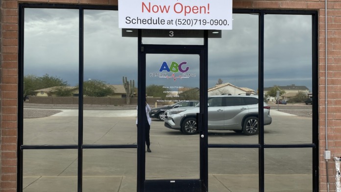 Exterior view of brick building entrance with large glass doors and windows, ABC Family Clinic signage displayed above