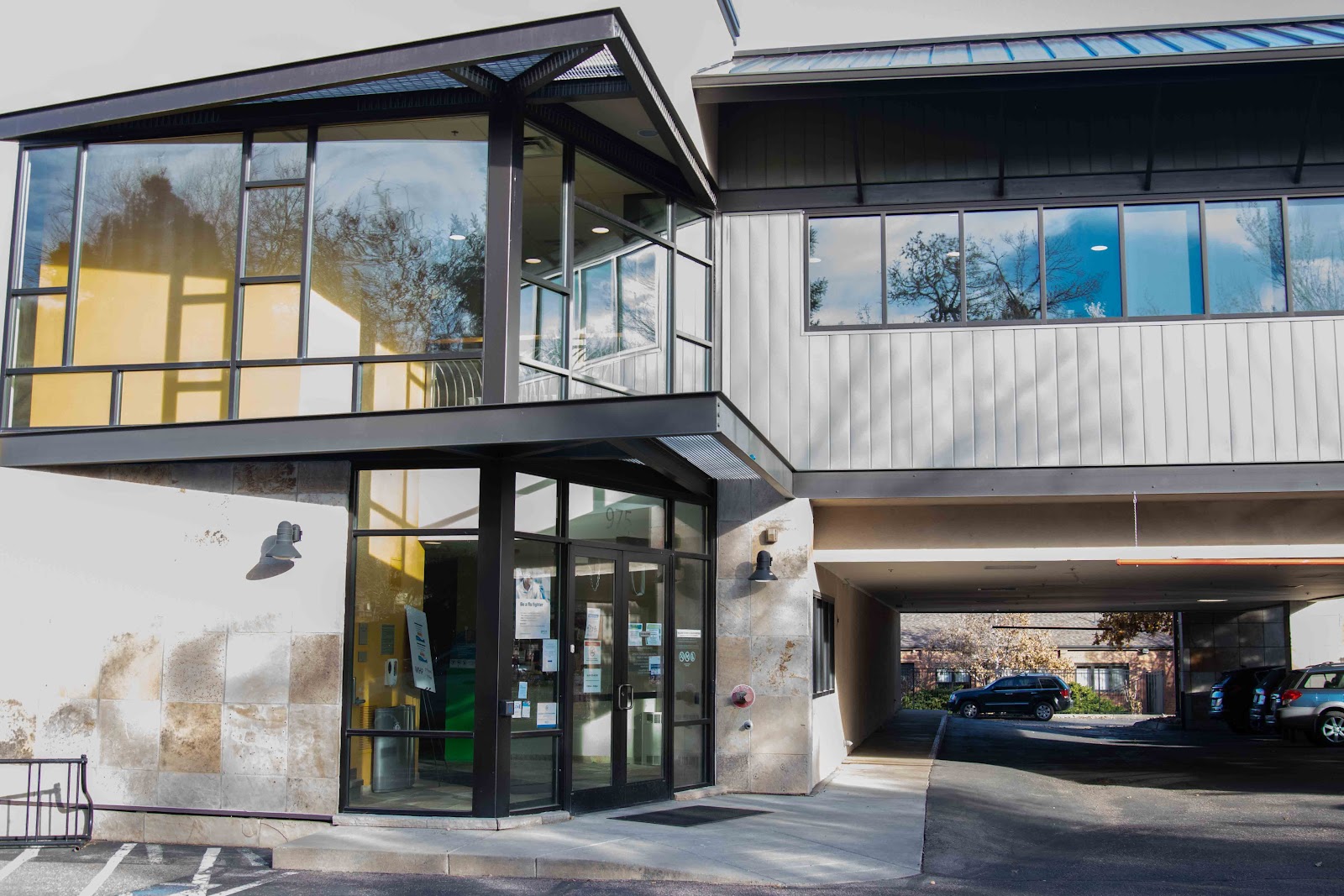 Exterior modern two-story treatment facility with black-framed windows, white metal siding, and covered entry