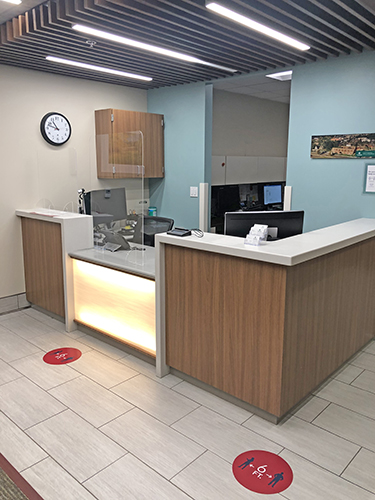 Interior reception counter with wood paneling, computer workstation, and clinical workspace for check-in and patient services