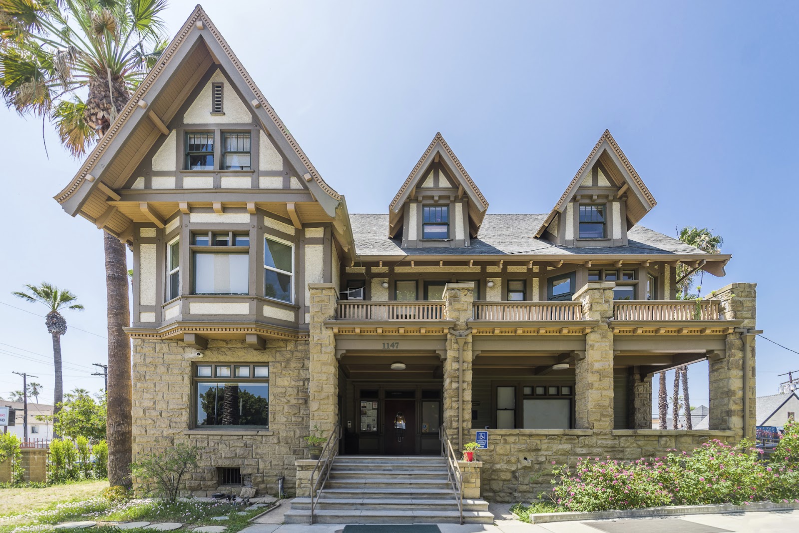 Full frontal view of ornate Victorian mansion with stone construction, multiple dormers, and historic architectural details