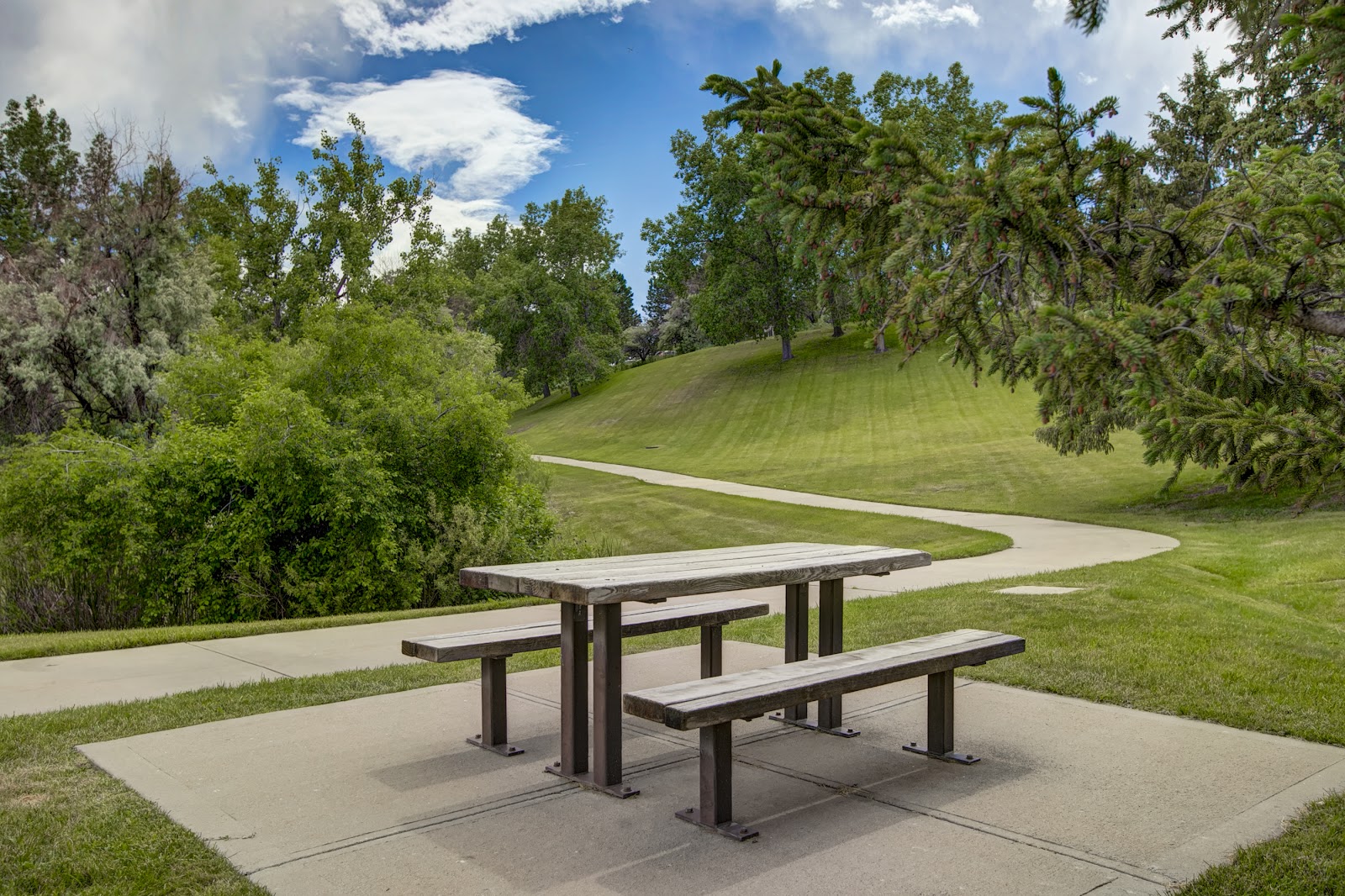 Outdoor facility grounds showing manicured lawn, winding concrete paths, and mature trees
