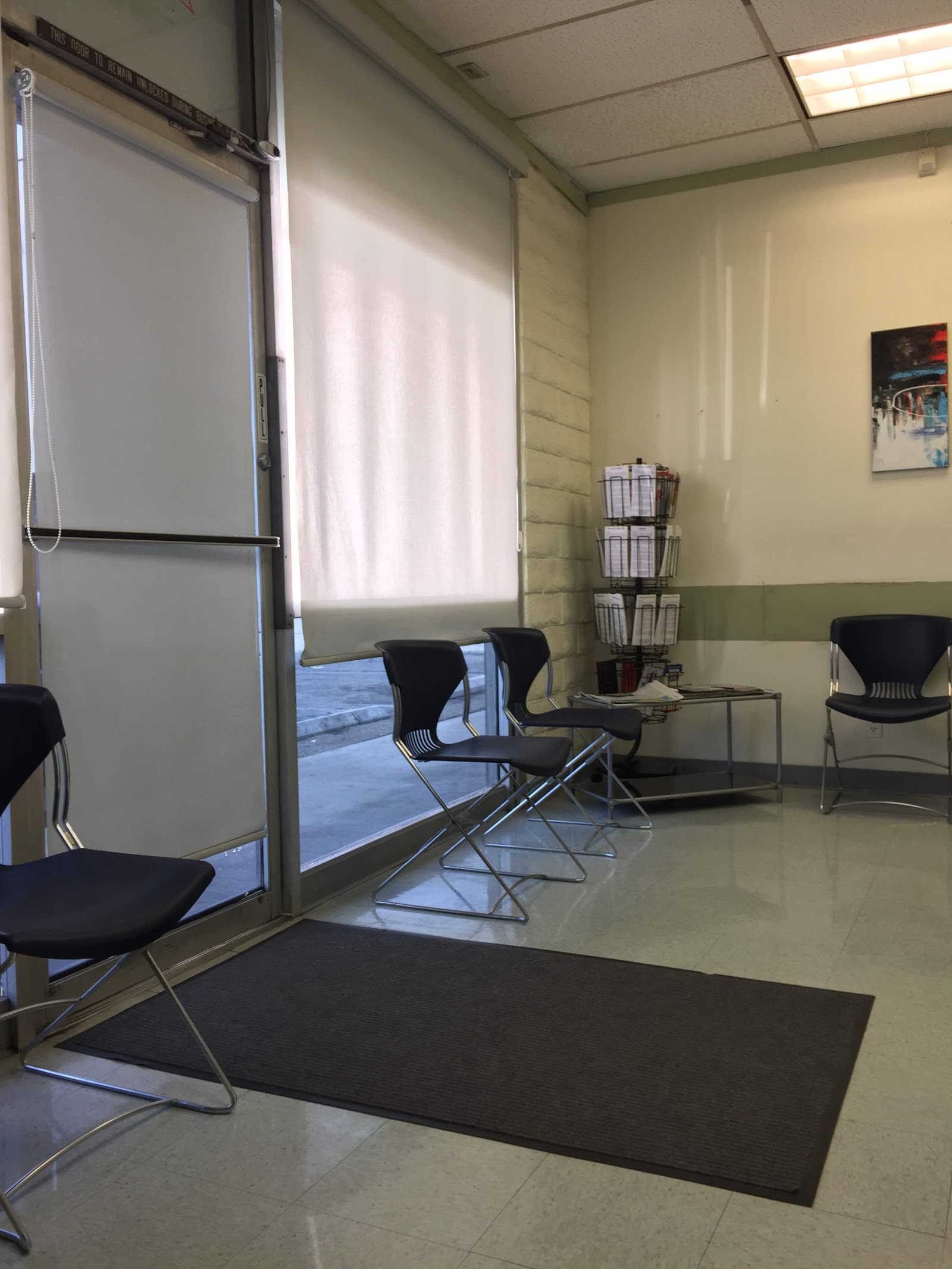 Interior activity room with multiple blue chairs, projector screen, storage, and windows