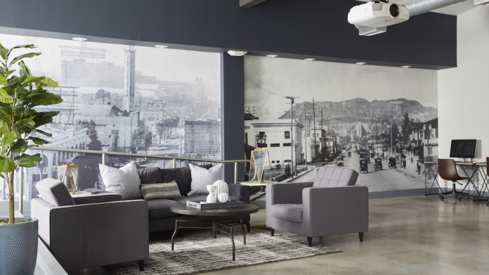 Interior common space with floor-to-ceiling windows overlooking cityscape, sectional seating, and black accent wall