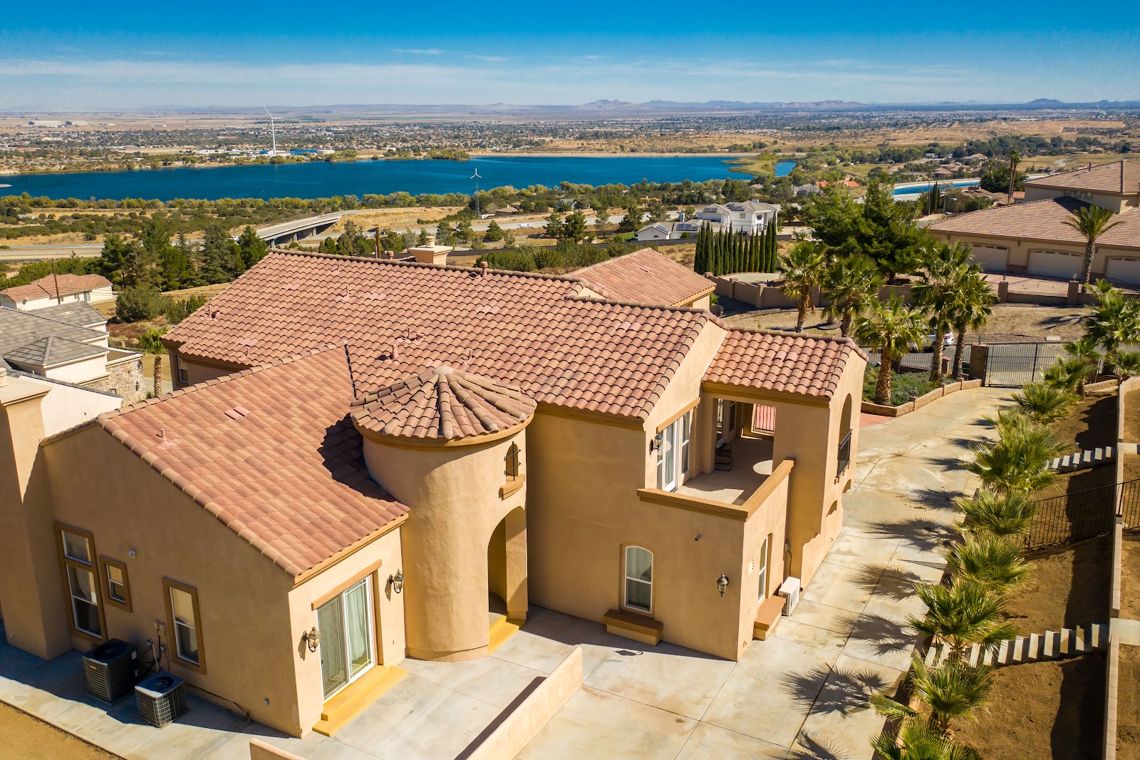 Exterior aerial view of residential facility showing Spanish-style architecture, tile roof, and scenic lake backdrop