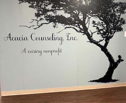 Interior view of Acacia Counseling logo wall with tree silhouette graphic and facility name displayed