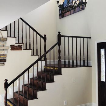 Interior staircase with dark wood steps, black metal railings, white walls, and decorative items on shelf