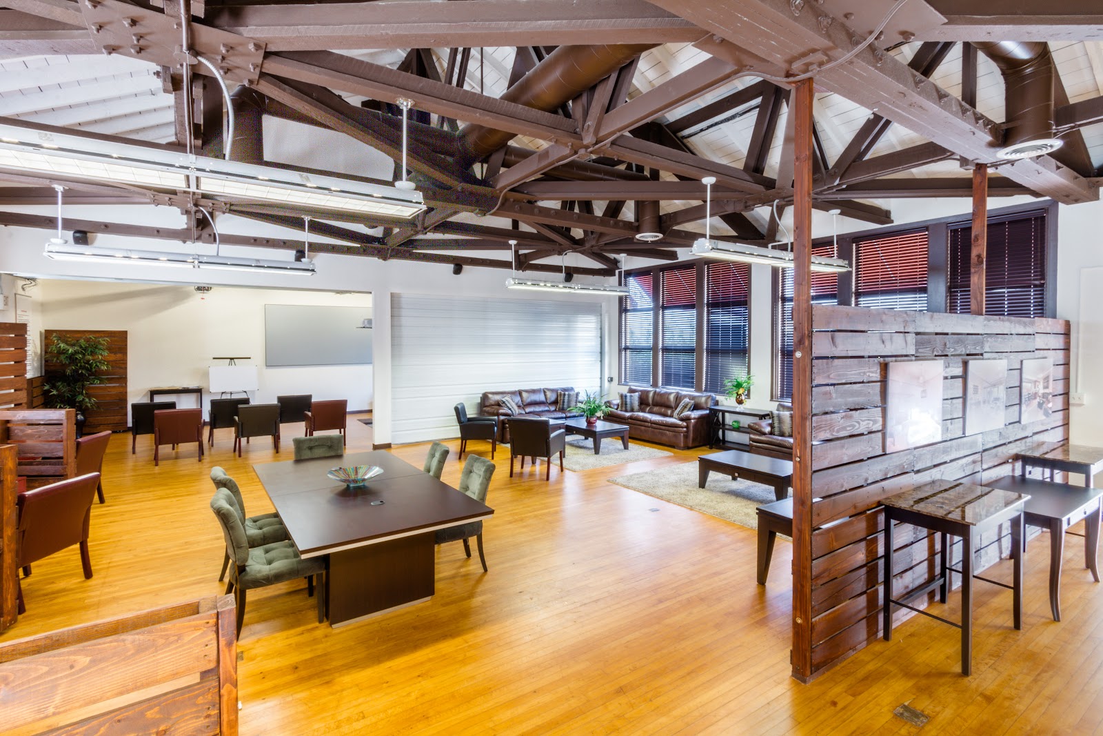 Interior open community space with wooden beam ceiling, multiple seating areas, and natural lighting