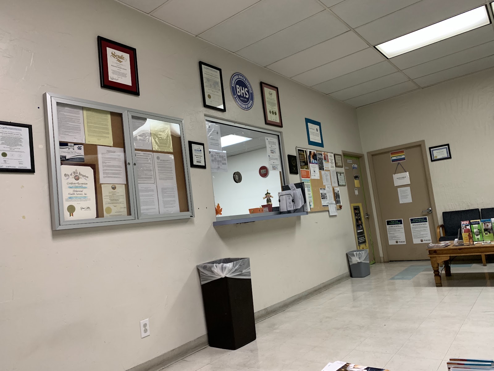 Interior lobby with reception desk, framed certifications on walls, waiting seating, and exit signage