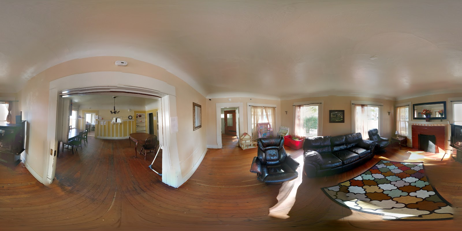 Interior lounge with black leather seating, wooden flooring, natural light, fireplace, and comfortable furnishings for residents