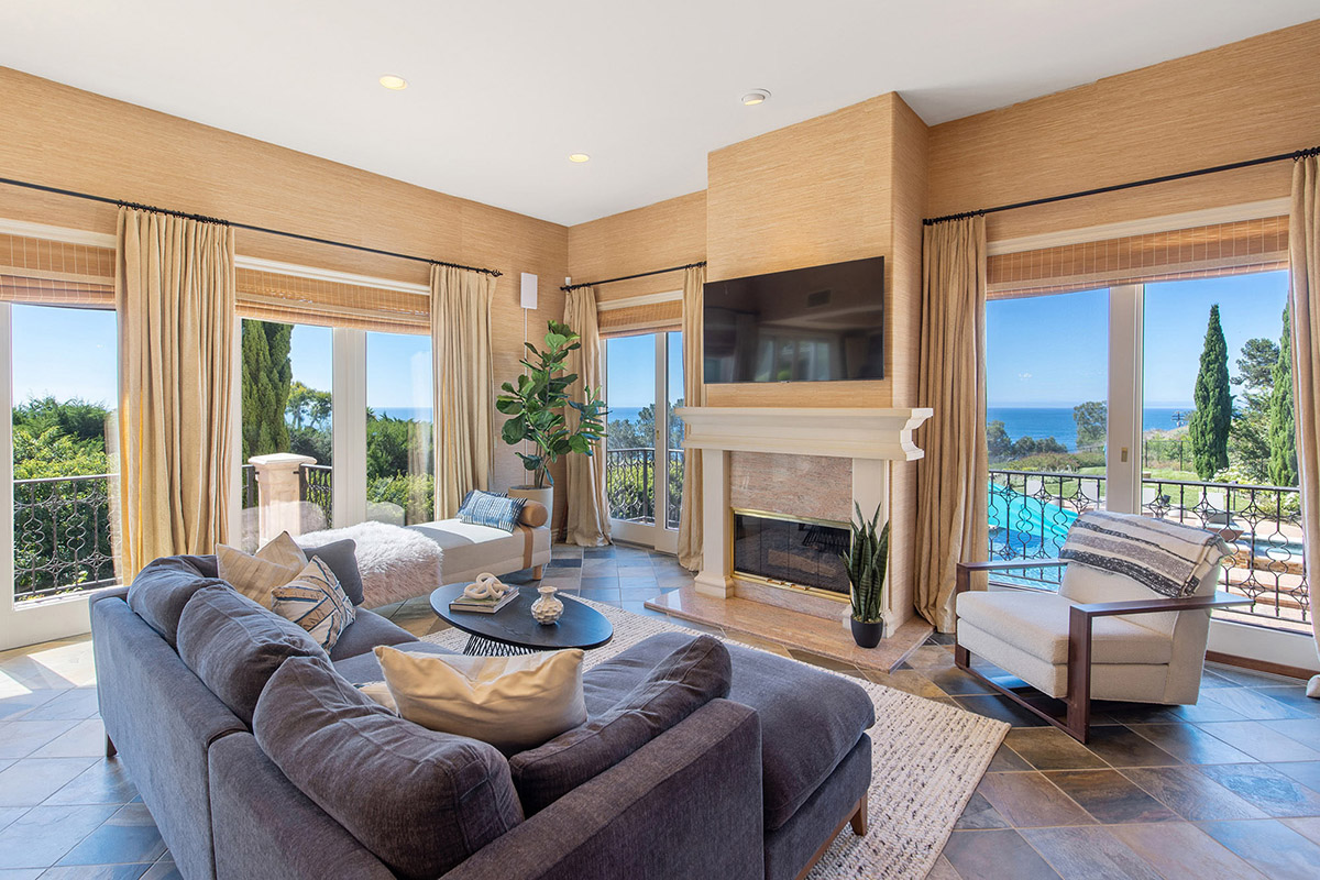 Interior living room with fireplace, ocean views through multiple windows, contemporary furnishings, and coastal décor