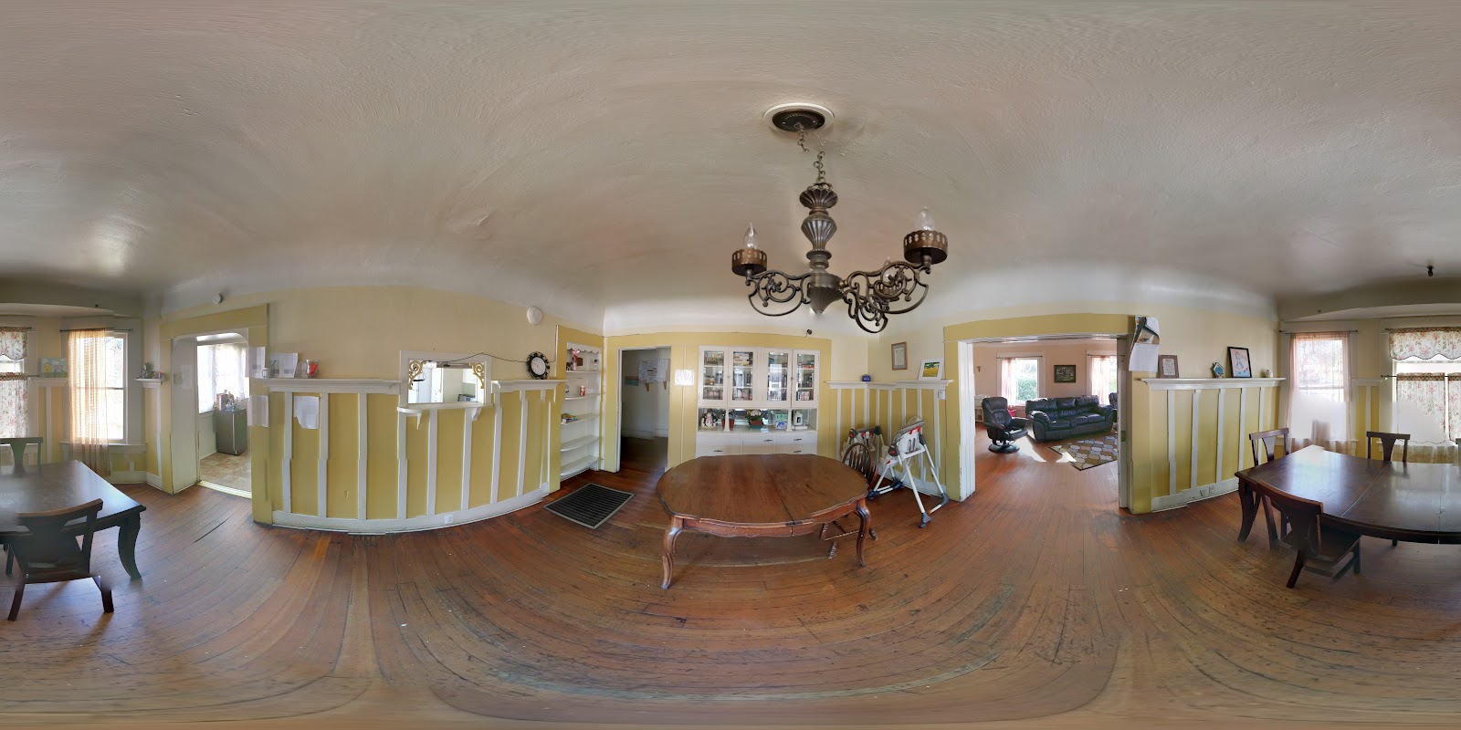 Interior common area with yellow walls, multiple seating areas, dining furniture, and natural lighting from windows