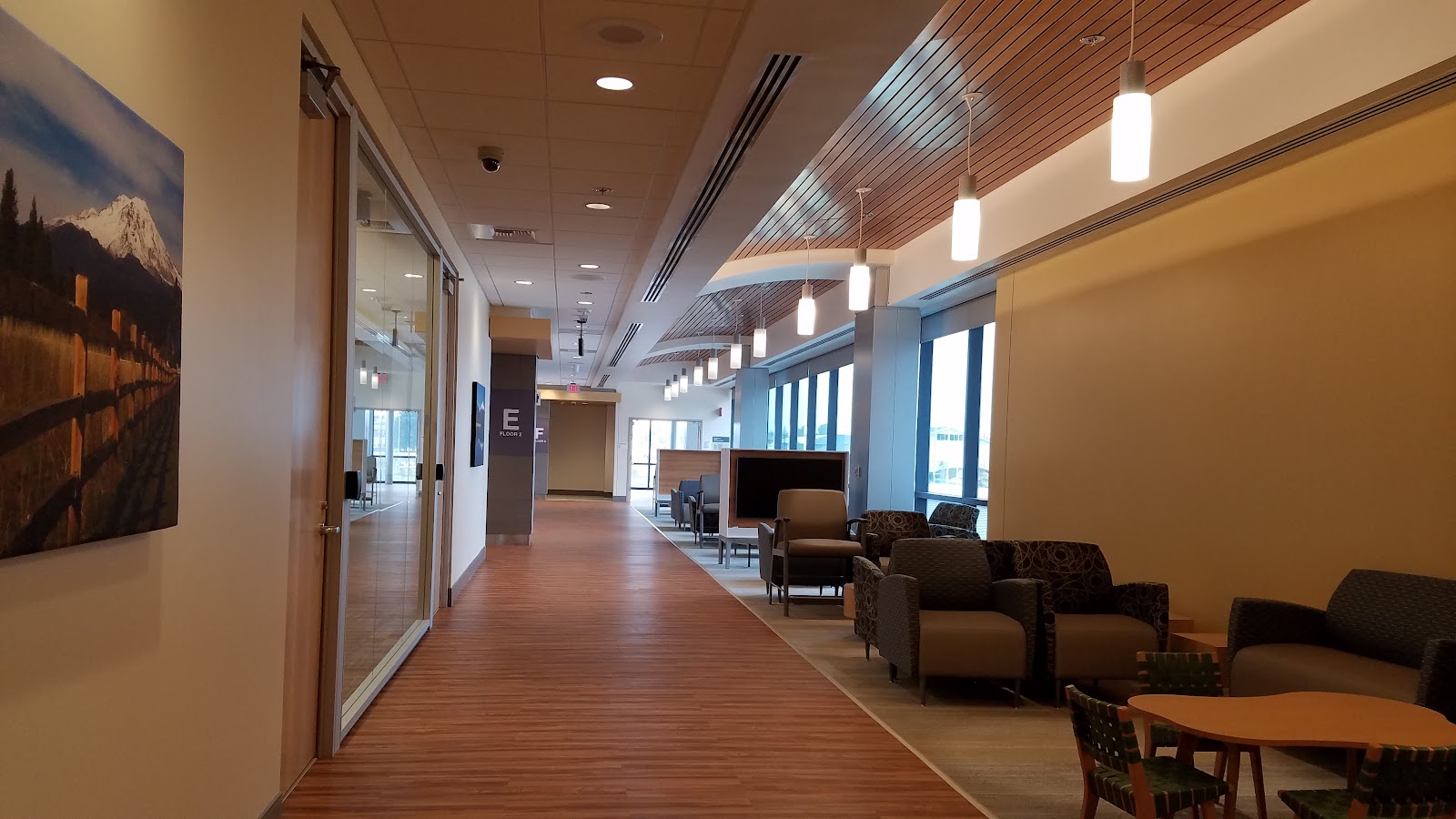 Interior hallway with lounge seating, artwork on walls, pendant lighting, and modern furnishings with natural light from windows