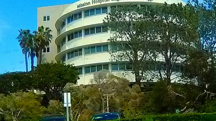 Exterior view of Mission Hospital Laguna Beach curved cream-colored building with landscaping and palm trees from street