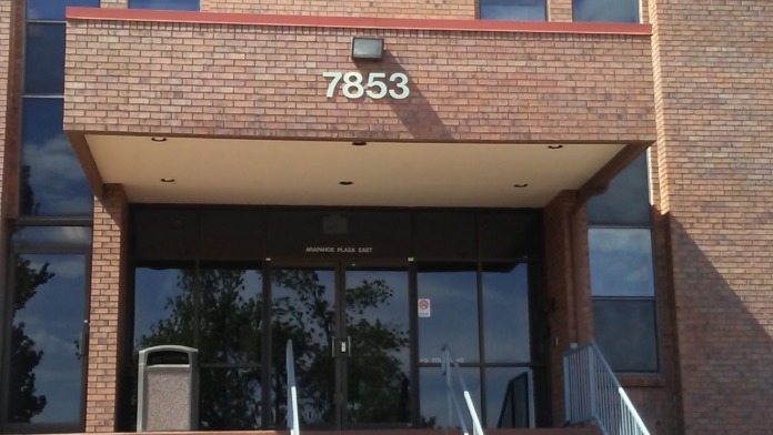Exterior of brick treatment facility building with address 7853, entrance steps with railings, tall windows, and metal awning.