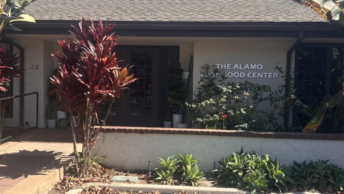 Exterior view of single-story treatment facility with beige stucco, landscaping, parking area, and signage.