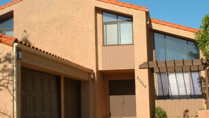 Exterior front entrance showing tan stucco residential building with address number and succulent garden beds