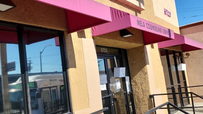 Exterior view of Mela Counseling Services center showing yellow building with pink awning, entrance at 5723, and clear signage