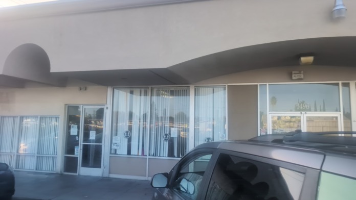 Exterior front entrance showing glass doors, windows with blinds, curved architectural elements, and facility signage