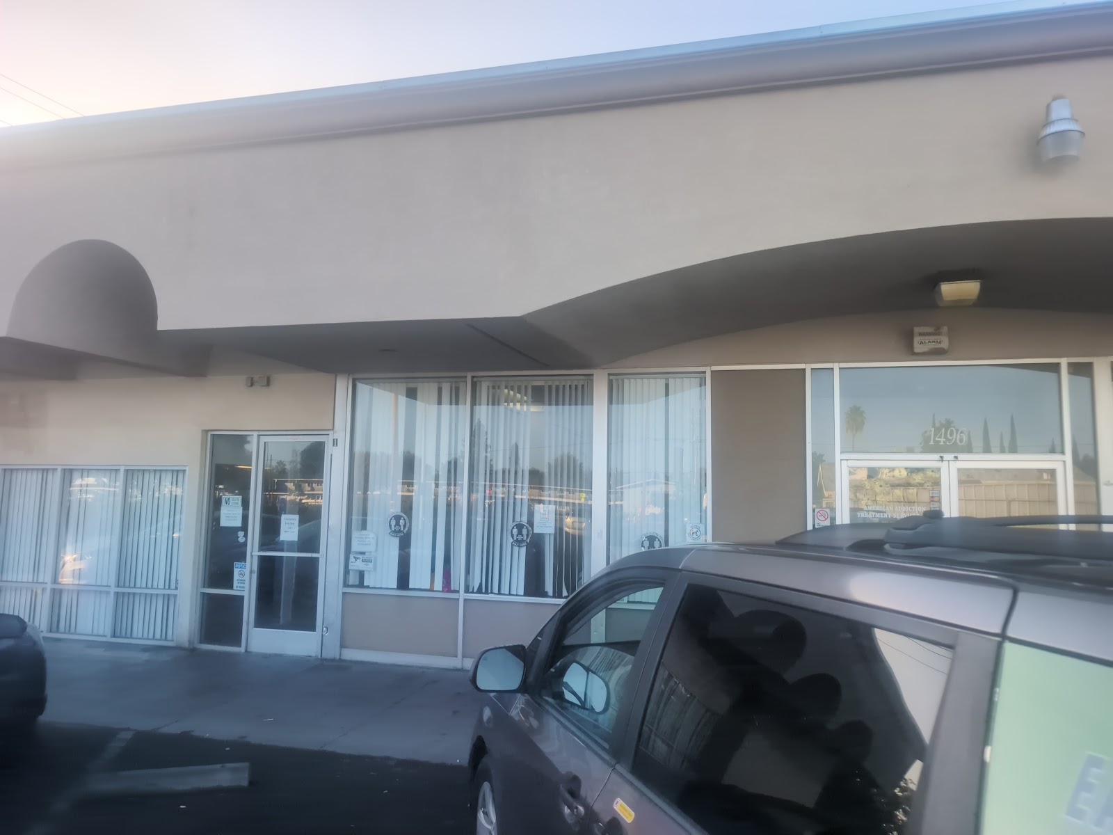 Exterior front entrance showing glass doors, windows with blinds, curved architectural elements, and facility signage