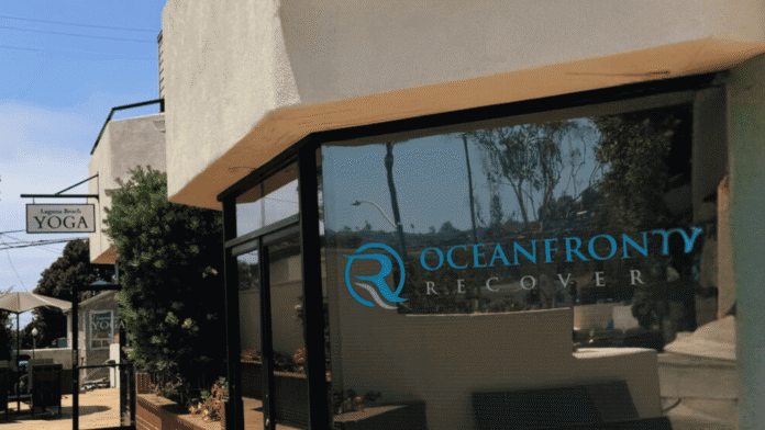 Exterior storefront displaying Oceanfront Recovery blue logo on glass doors and curved white facade with landscaping