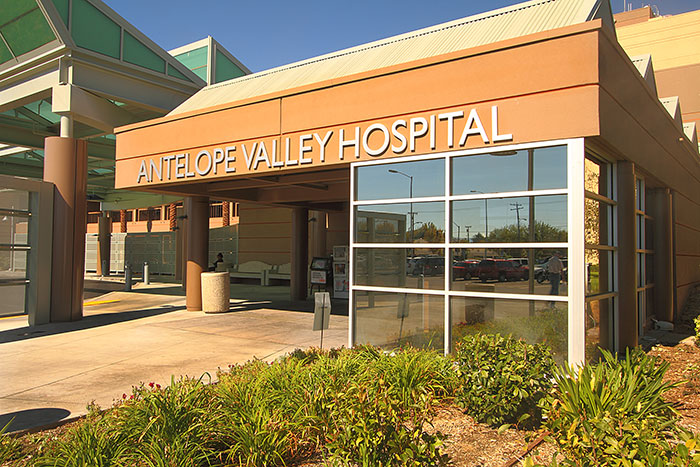Exterior view of main entrance with Antelope Valley Hospital sign, glass doors, landscaping, and metal canopy structure
