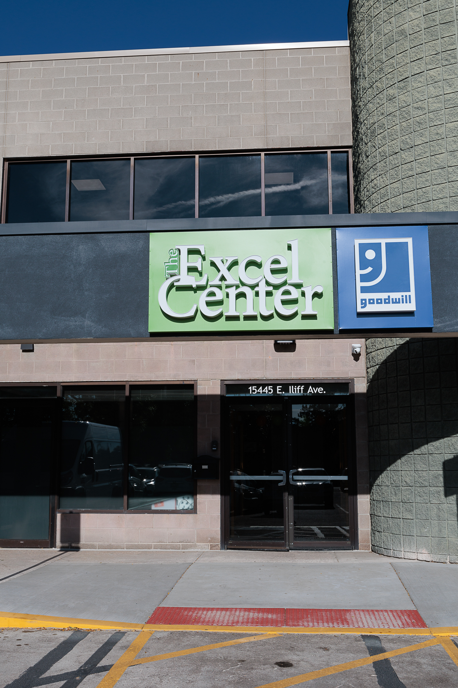 Exterior front entrance showing Excel Center green logo sign and Goodwill signage on brick building facade