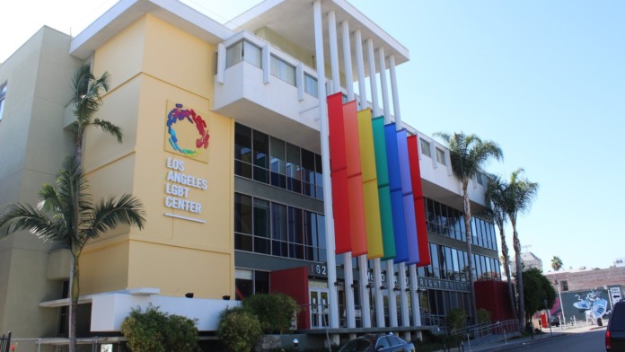 Exterior of Los Angeles LGBT Center showing yellow building with colorful rainbow support columns and facility signage