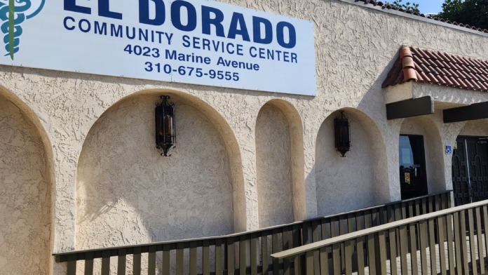Exterior view of El Dorado Community Service Center at 4023 Marine Avenue showing main entrance with arched doorways, accessibility ramp, and facility signage against cream-colored stucco building