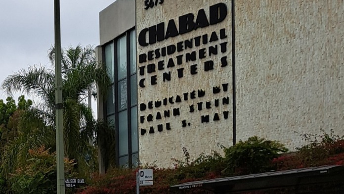 Exterior building facade showing Chabad Residential Treatment Centers signage with address, landscaped grounds, and street frontage
