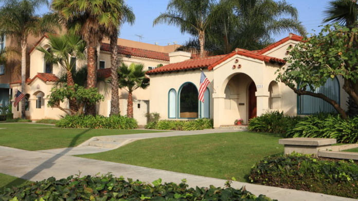 Exterior of Spanish-style treatment center with cream walls, red tile roof, palm trees, and manicured landscaping