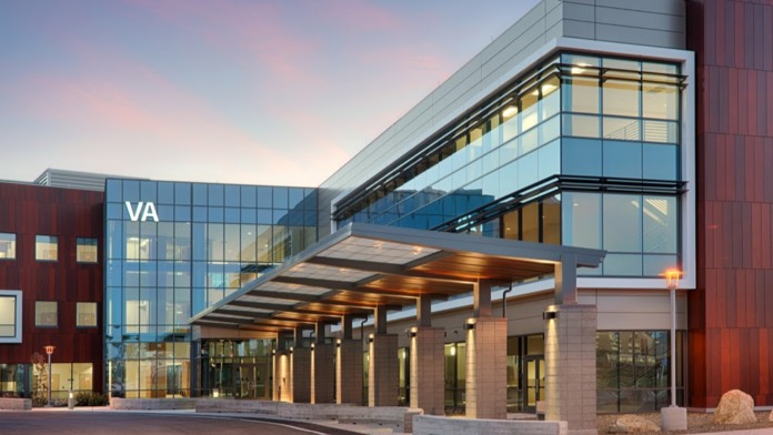 Exterior front entrance of VA Palo Alto Health Care System featuring modern glass and brick architecture with VA signage and covered entry portico