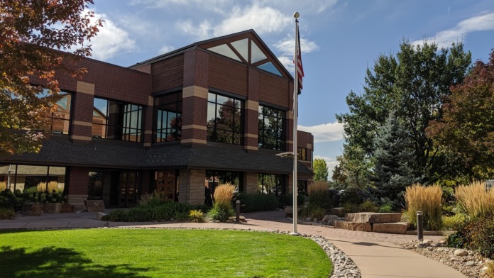 Exterior front facade of brick treatment center with large windows, manicured lawn, decorative landscaping, and curved walkway