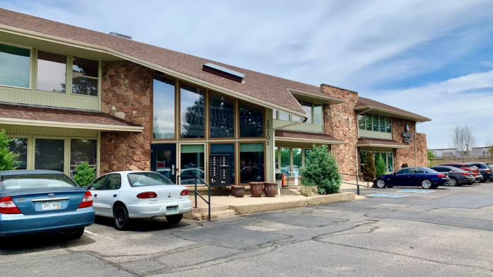 Exterior view of treatment facility showing brick facade, main entrance with glass doors, and visitor parking area with multiple vehicles