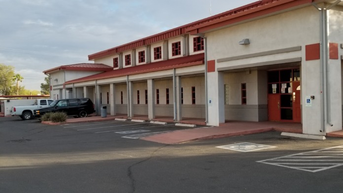 Exterior view of treatment facility showing main entrance with red roof, covered portico, parking area, and landscaping