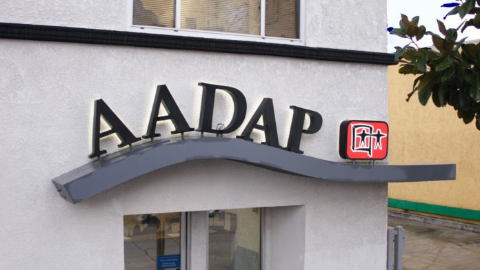 Exterior front entrance of AADAP facility at 5318 South Crenshaw Boulevard showing white building facade with red cross symbol and address number