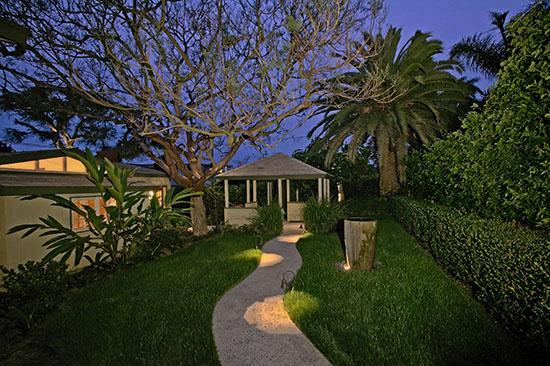 Exterior showing nighttime view of main building entrance with illuminated curved walkway, landscaping, and tropical vegetation