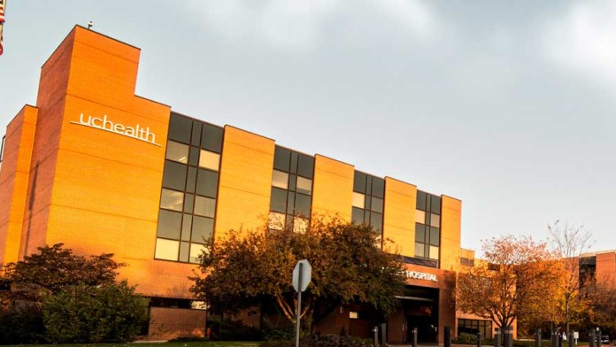 Exterior of modern behavioral health center with distinctive yellow and orange facade, gridded windows, landscaping, and UCHealth signage