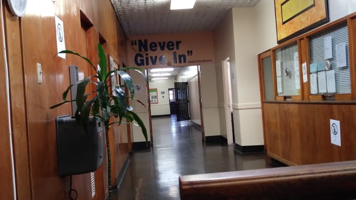 Interior hallway with wood paneling, motivational signage, potted plant, and staff directory board