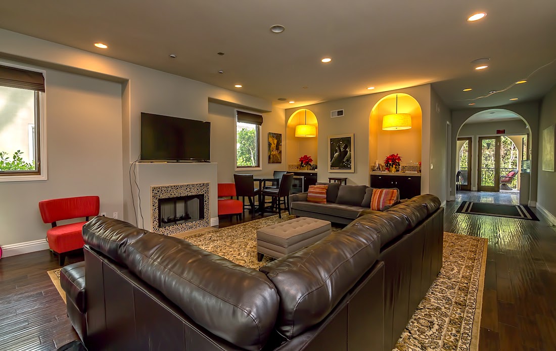 Interior common living area with fireplace, leather seating, television, decorative artwork, and elegant lighting throughout