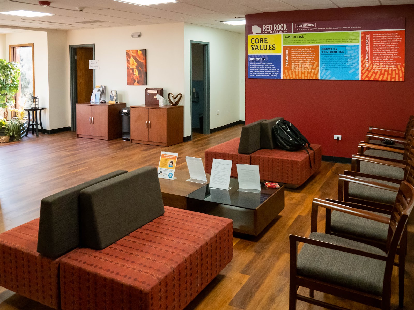 Interior lobby space with Red Rock Recovery Center branding, colorful mission statement signage, and modern furniture