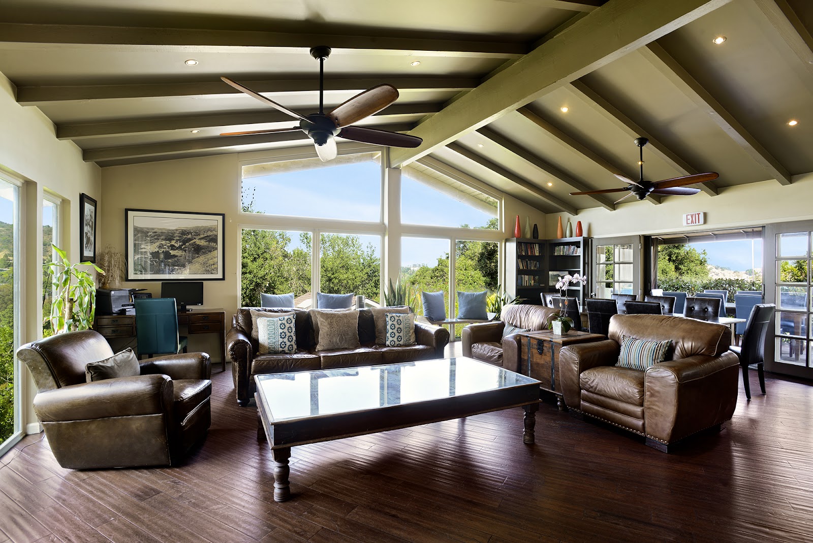 Interior lounge featuring leather seating, ceiling fans, natural light, and expansive views of hillside landscape