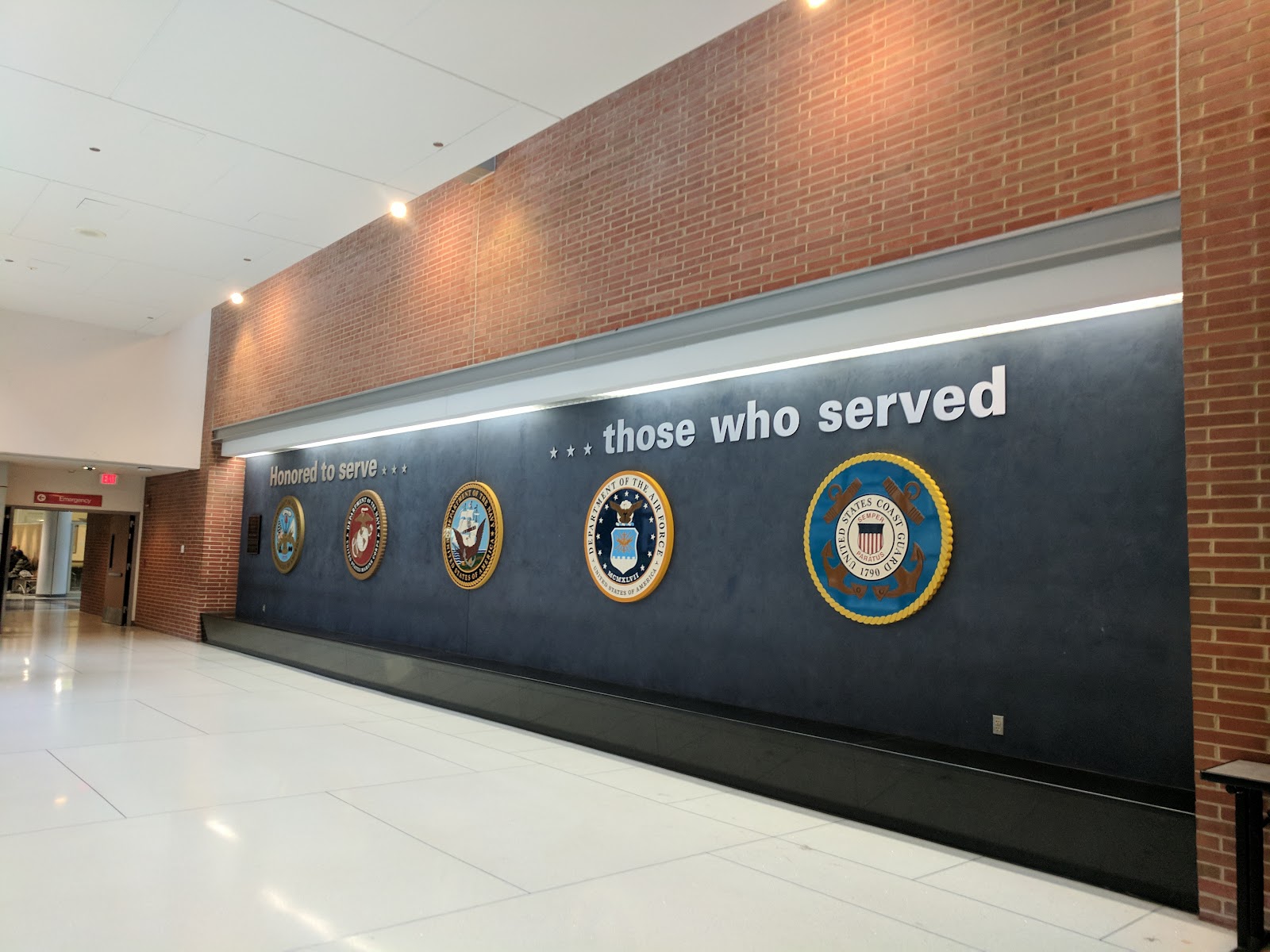 Interior lobby display wall featuring military service seals with text honoring those who served