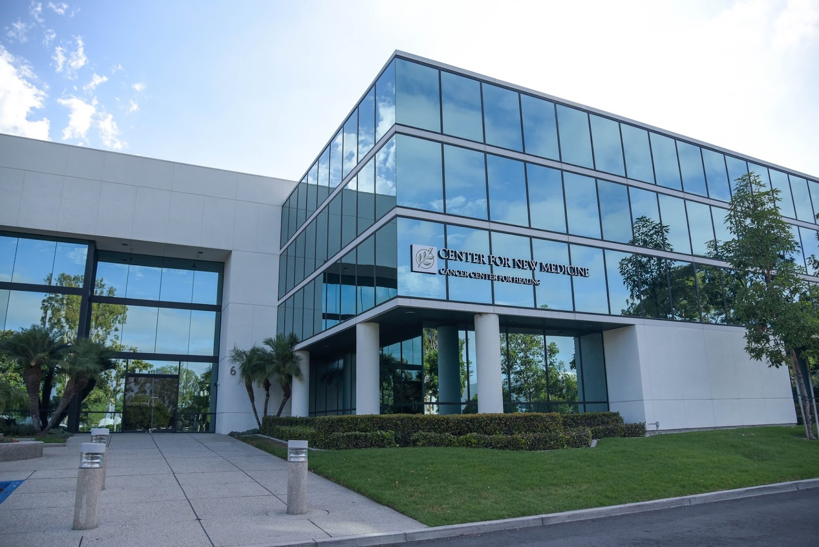 Exterior of modern white building with extensive glass windows, landscaped grounds, and facility signage
