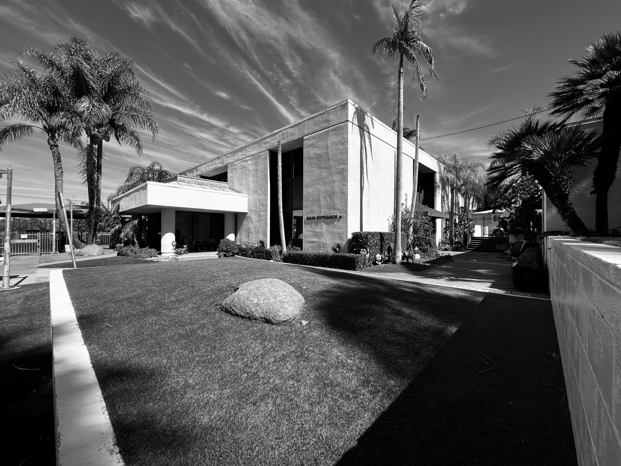 Exterior view of contemporary treatment facility building with landscaping, palm trees, and manicured grounds in black and white
