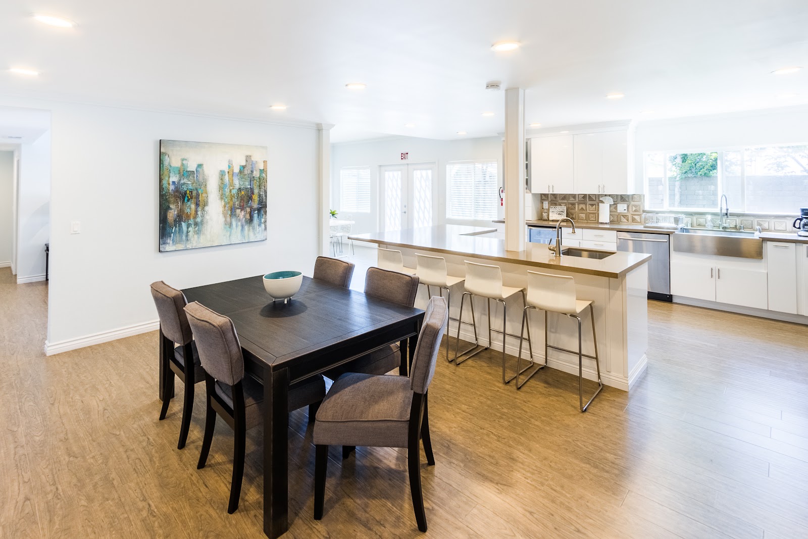 Interior kitchen with white cabinetry, stainless steel appliances, dining table, and bar seating