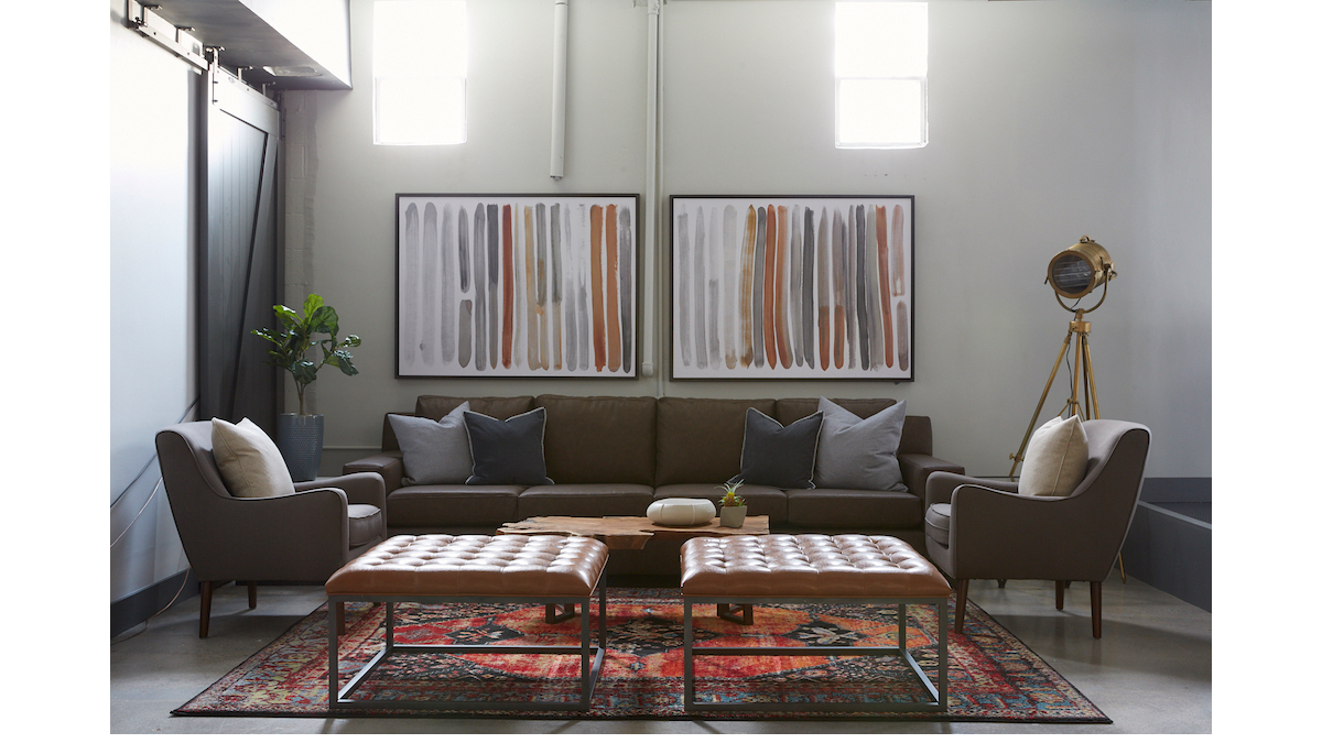 Interior lounge space with dark brown sectional sofa, armchairs, framed wall art, and neutral finishes