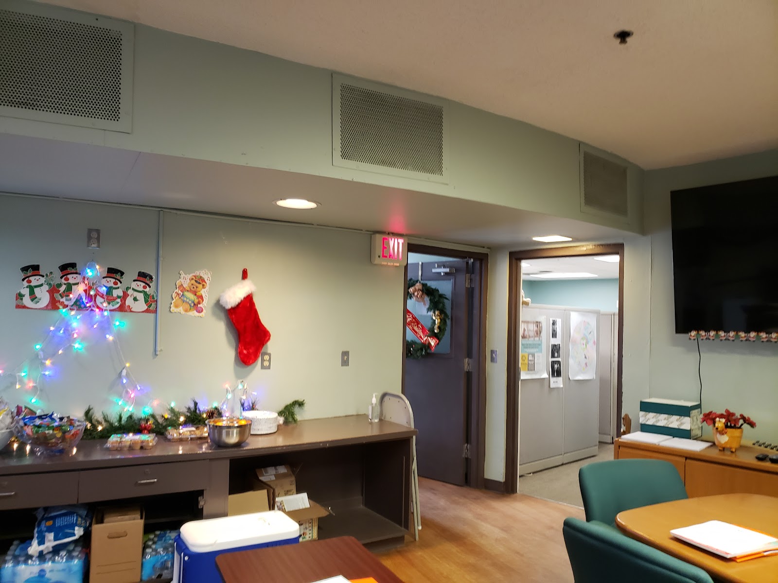 Interior activity space with decorated walls, Christmas tree, festive ornaments, tables with chairs, and storage areas