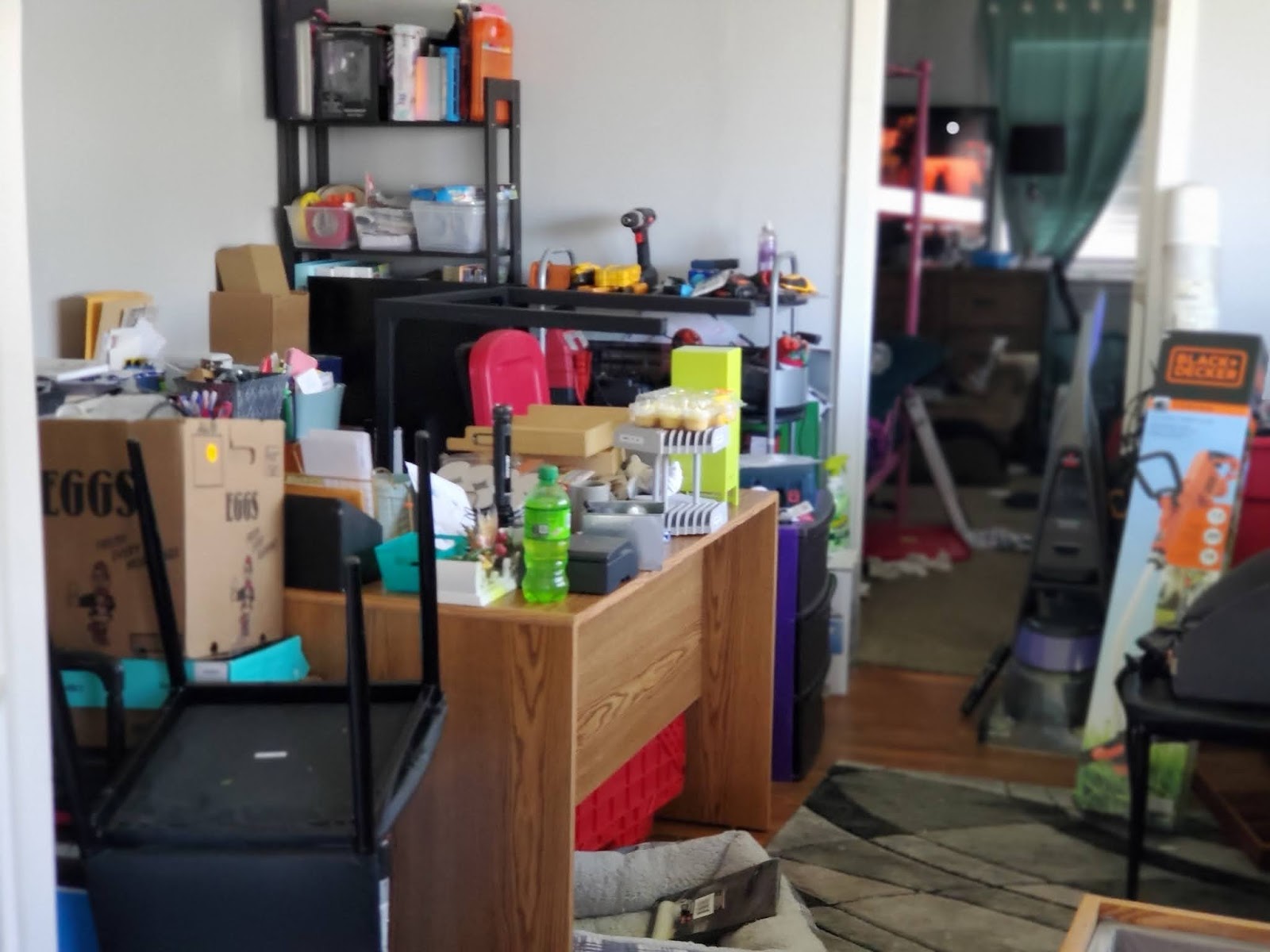 Interior workspace with wooden desk, shelving units, storage containers, and organized office supplies.
